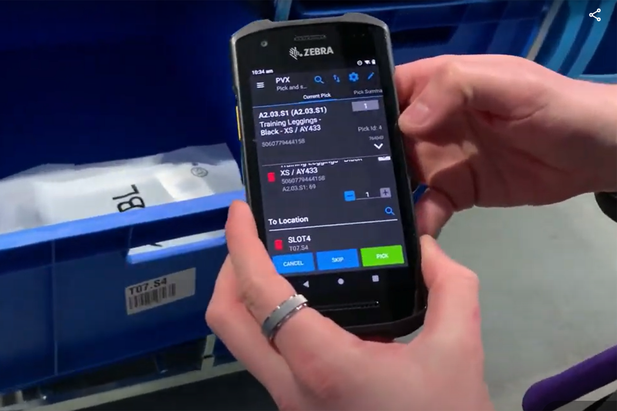 Warehouse worker holds Zebra mobile device running the Descartes Peoplevox Android-based WMS