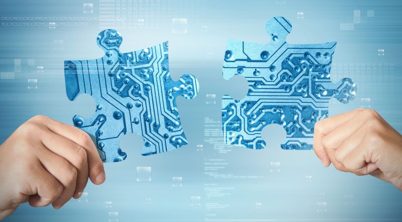 Two hands move computer chip puzzle pieces together
