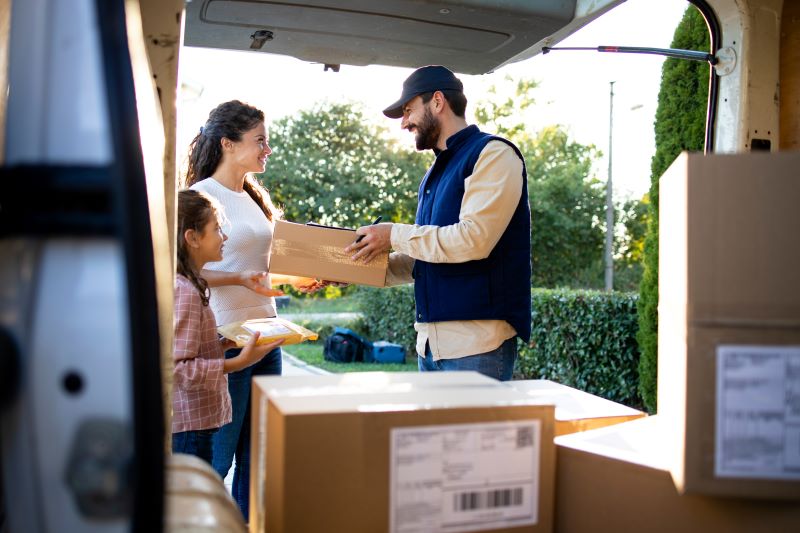Delivery driver hands package to woman and child