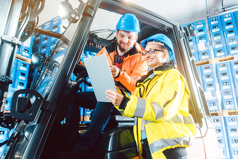 Two fleet distribution workers look at clipboard with order information in distribution center