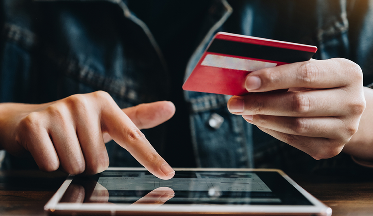 An multichannel ecommerce shopper holding a credit card uses a tablet to make an online purchase.