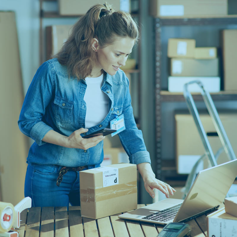Lady in a denim shirt using a laptop with shipping software