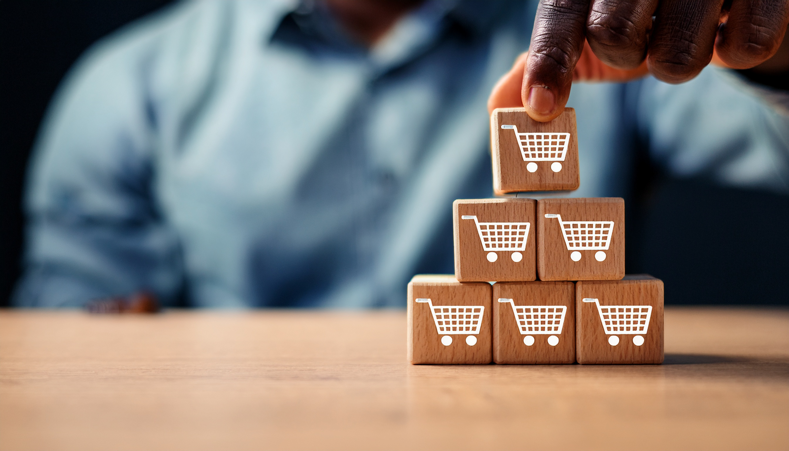 A person stacks blocks with shopping carts on them, representing adding sales channels.