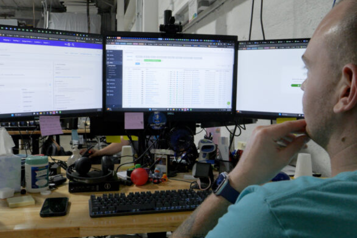 Warehouse worker using the Descartes Sellercloud ecommerce operations platform to manage inventory on a desktop computer