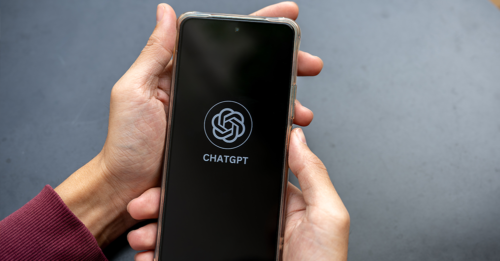 An image of someone holding a mobile device featuring the ChatGPT logo.