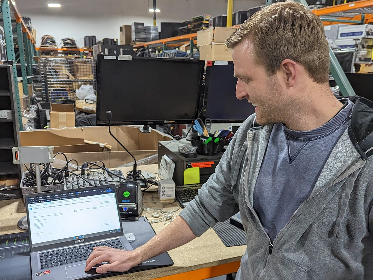Warehouse worker using a computer with Descartes Finale inventory software to maintain accurate inventory across Shopify, Amazon, Walmart, and eBay sales channels