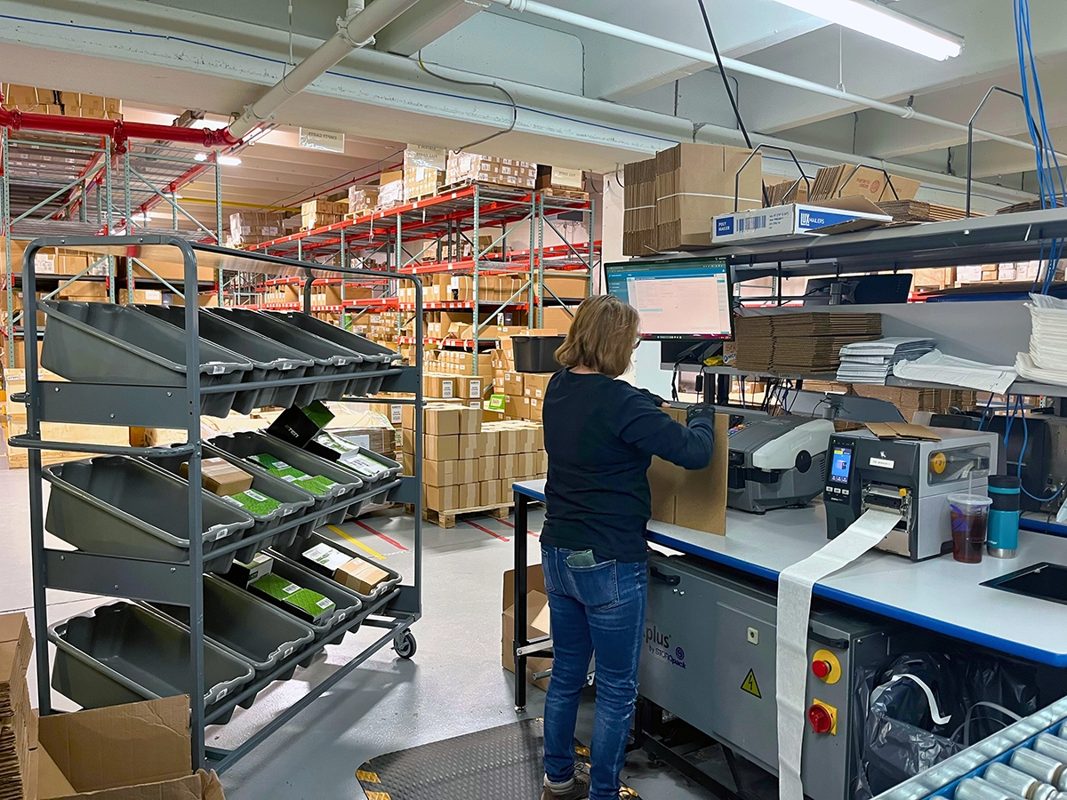 Shipping station worker building a box for multi-carrier ecommerce shipping