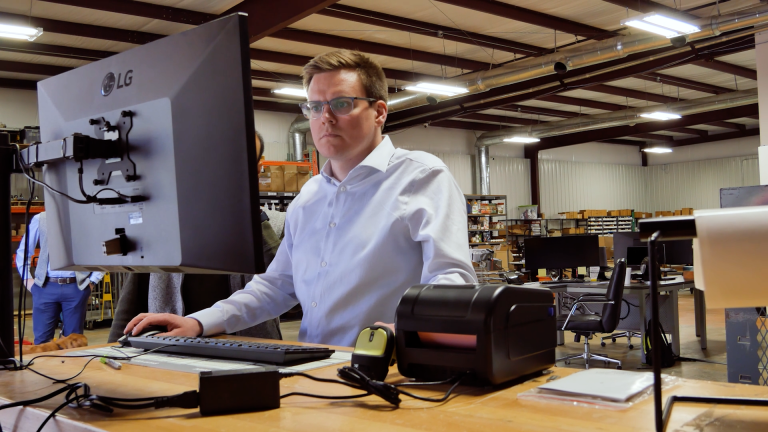 A warehouse manager uses a desktop computer with FBA purchase order software to calculate  how much to restock for FBA.