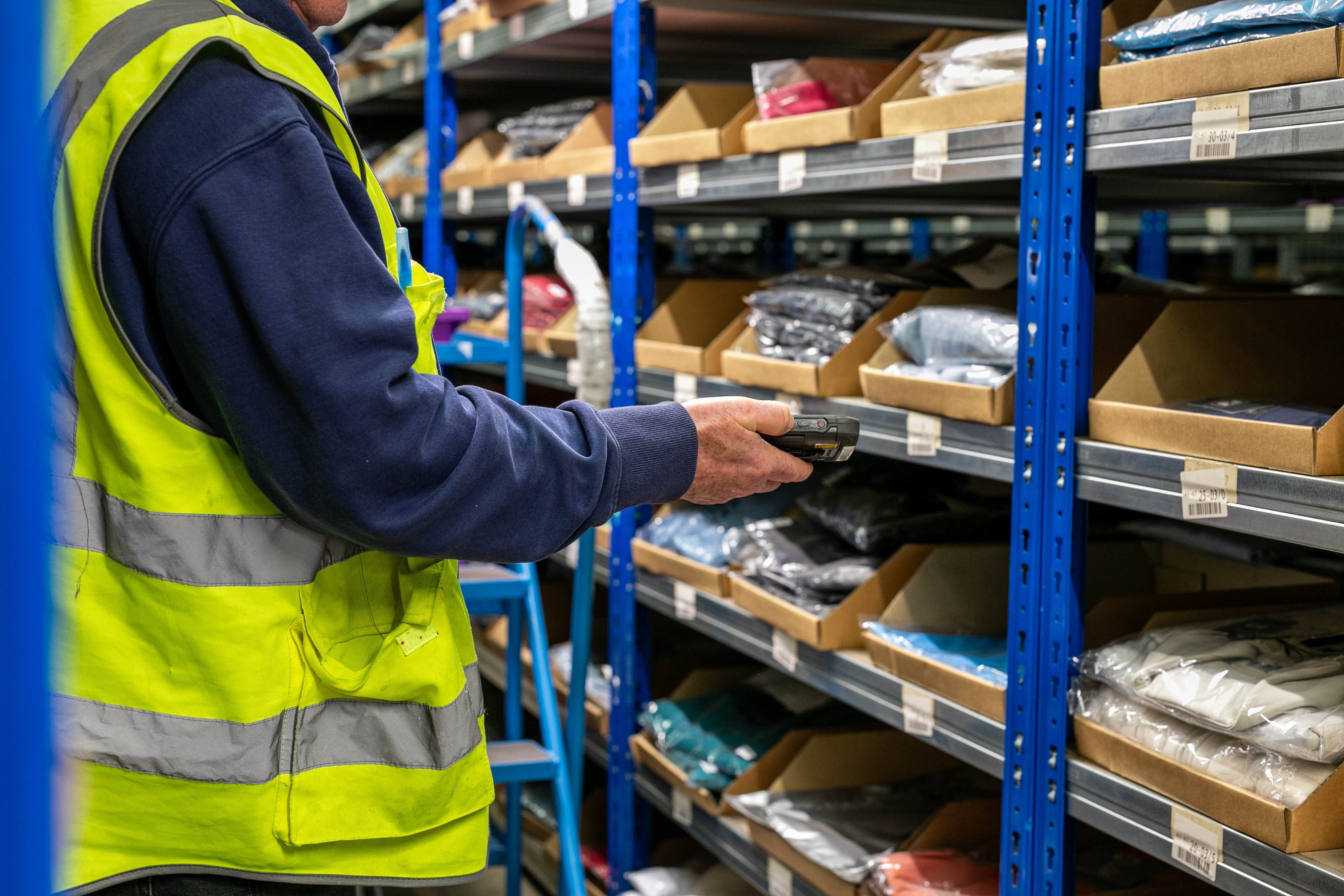 Warehouse worker scanning inventory with a handheld barcode scanner to verify stock accuracy and improve order fulfillment.