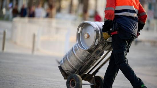 Beverage distribution worker moves kegs on trolley