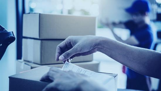 Person placing a low-cost shipping label on a parcel