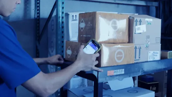 Warehouse worker holding a mobile barcode scanning device with a warehouse management system (WMS) picking orders in a warehouse