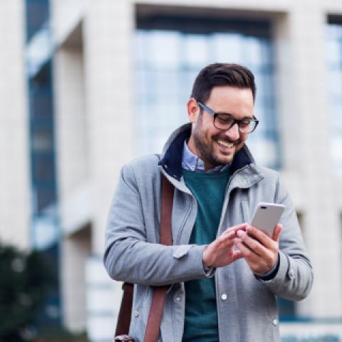 An image of a man smiling while looking at his phone