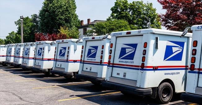 An image showing several parked USPS delivery trucks.